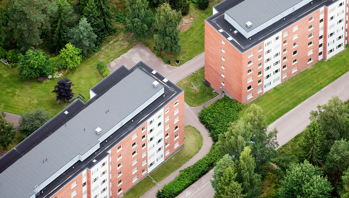 Två flerbostadshus samt grönytor fotograferade ovanifrån.